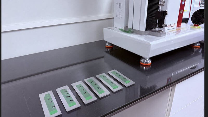 Prepared release liner test strips arranged beside a tester for multi-property evaluation