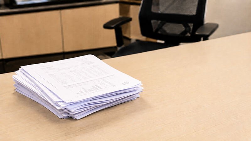 Thick stack of qualification documents on an office desk