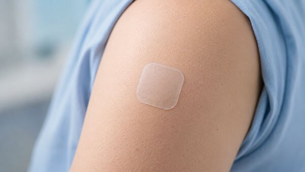 Transdermal drug delivery patch applied to a patient's upper arm.
