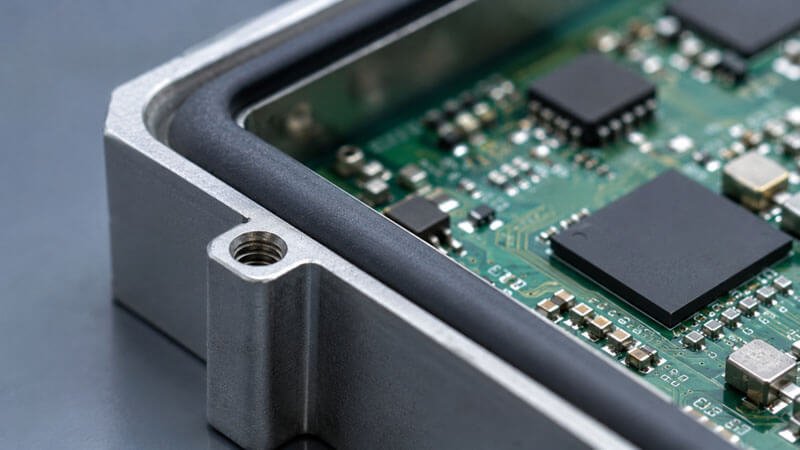 Conductive silicone EMI gasket sealing a metal shielding frame around a circuit board — fluorosilicone release liner for conductive silicone coatings